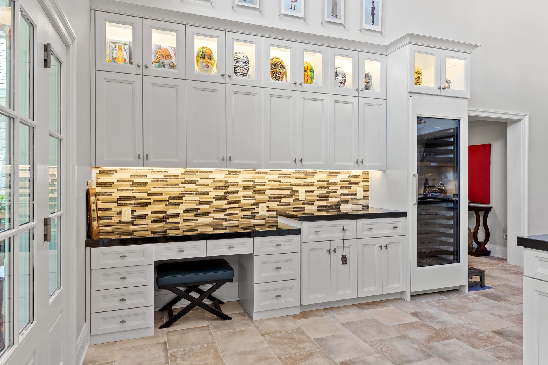 White kitchen cabinets with built-in desk, tiled backsplash, and wine cooler; neutral tones.