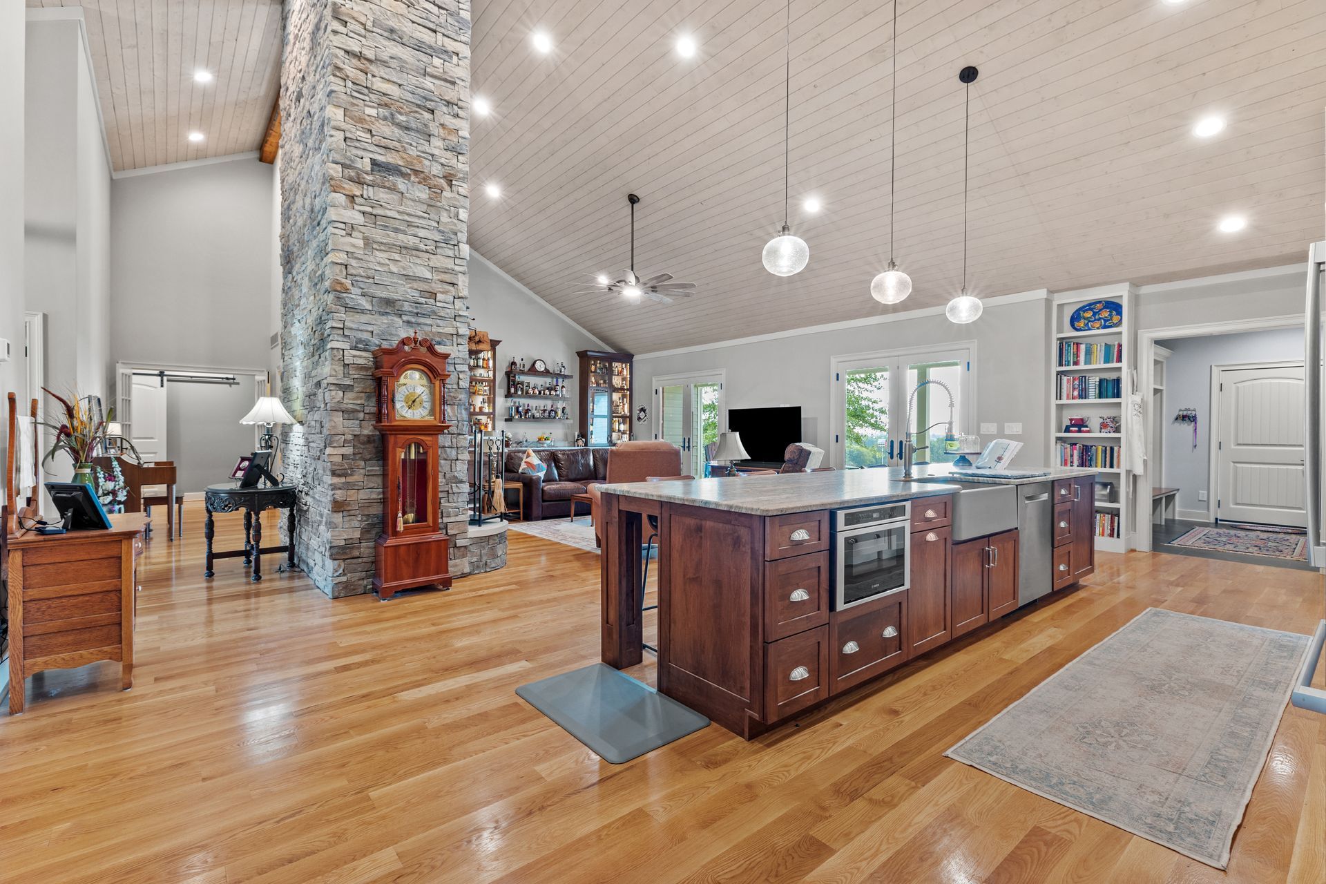 Spacious kitchen with a large island, stone chimney, and hardwood floors.