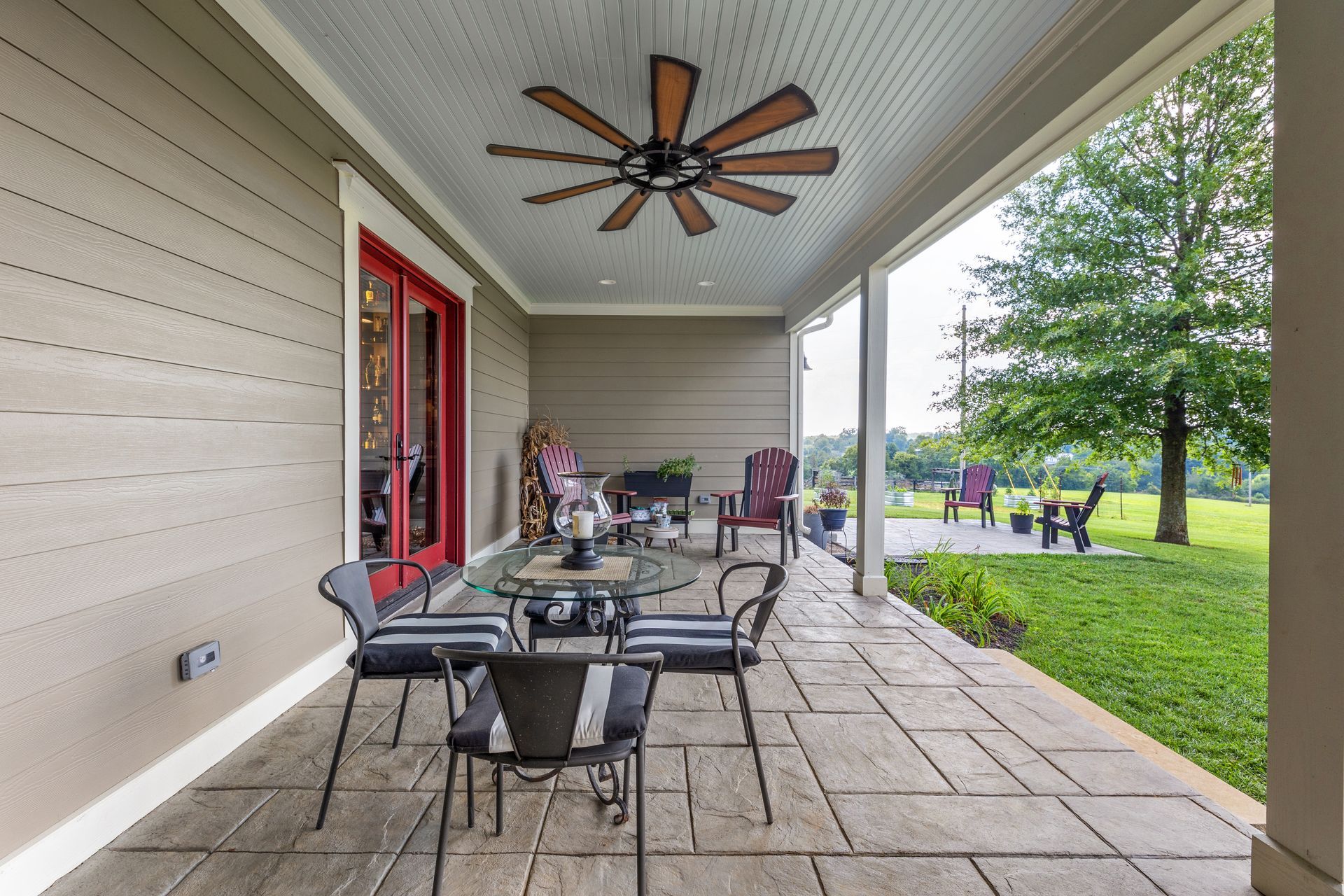 Covered patio with seating, ceiling fan, and view of lawn.