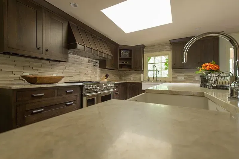 Dark wood kitchen with stone backsplash, stainless steel appliances, and a large sink.