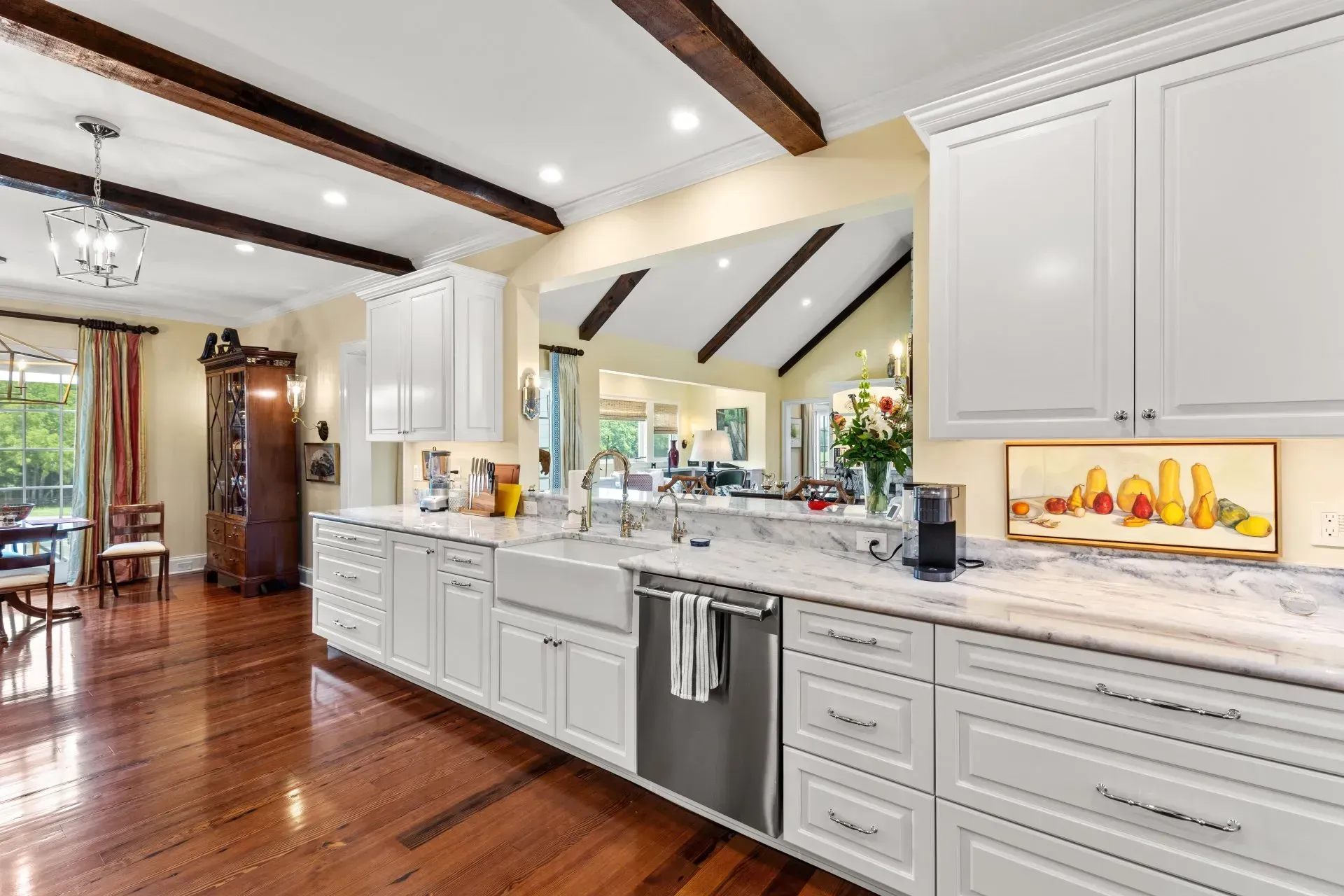 White kitchen with cabinets, stainless steel appliances, marble countertops, and dark wood floors.