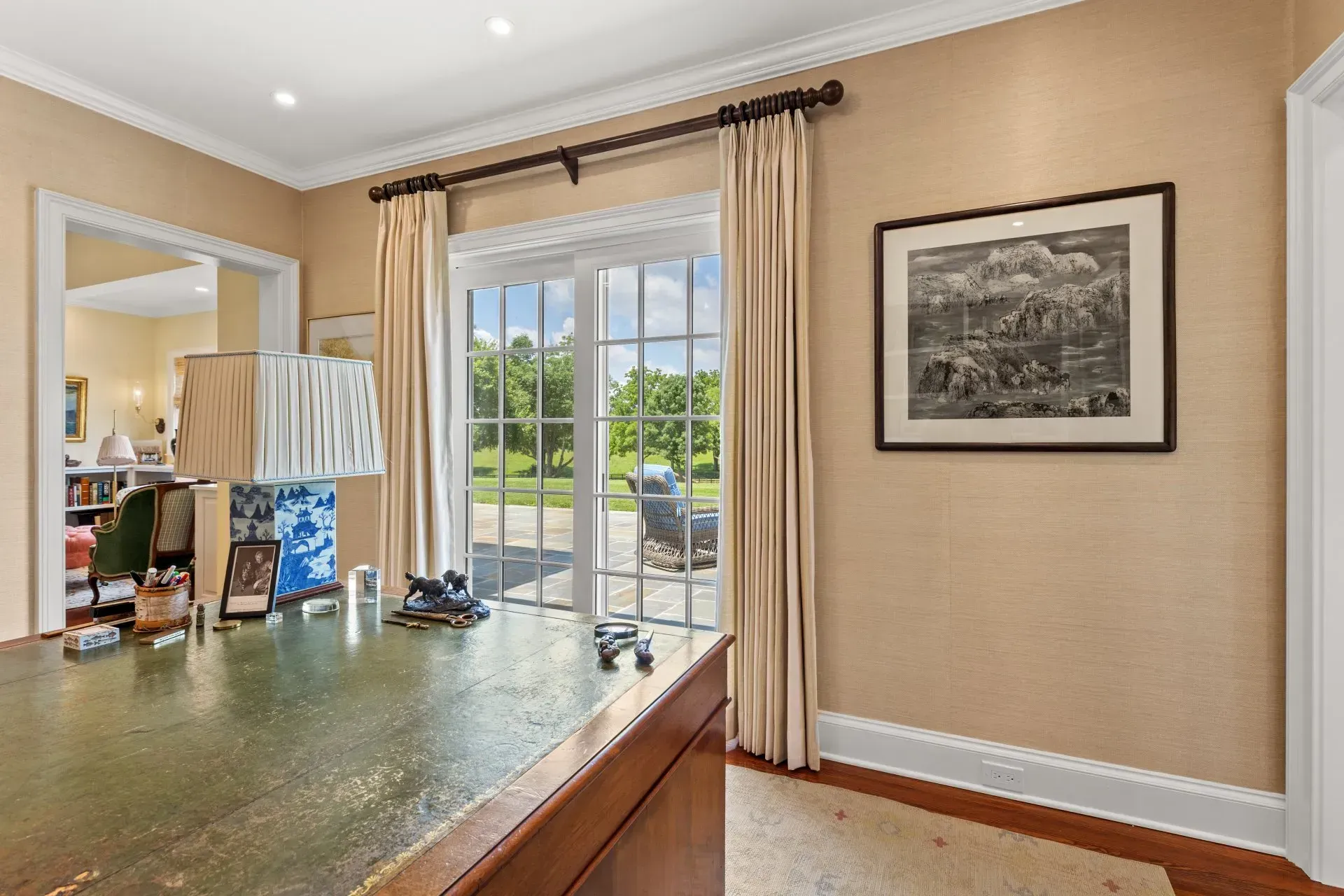 Office with desk, French doors to a yard, artwork on wall, light-colored walls, and white trim.