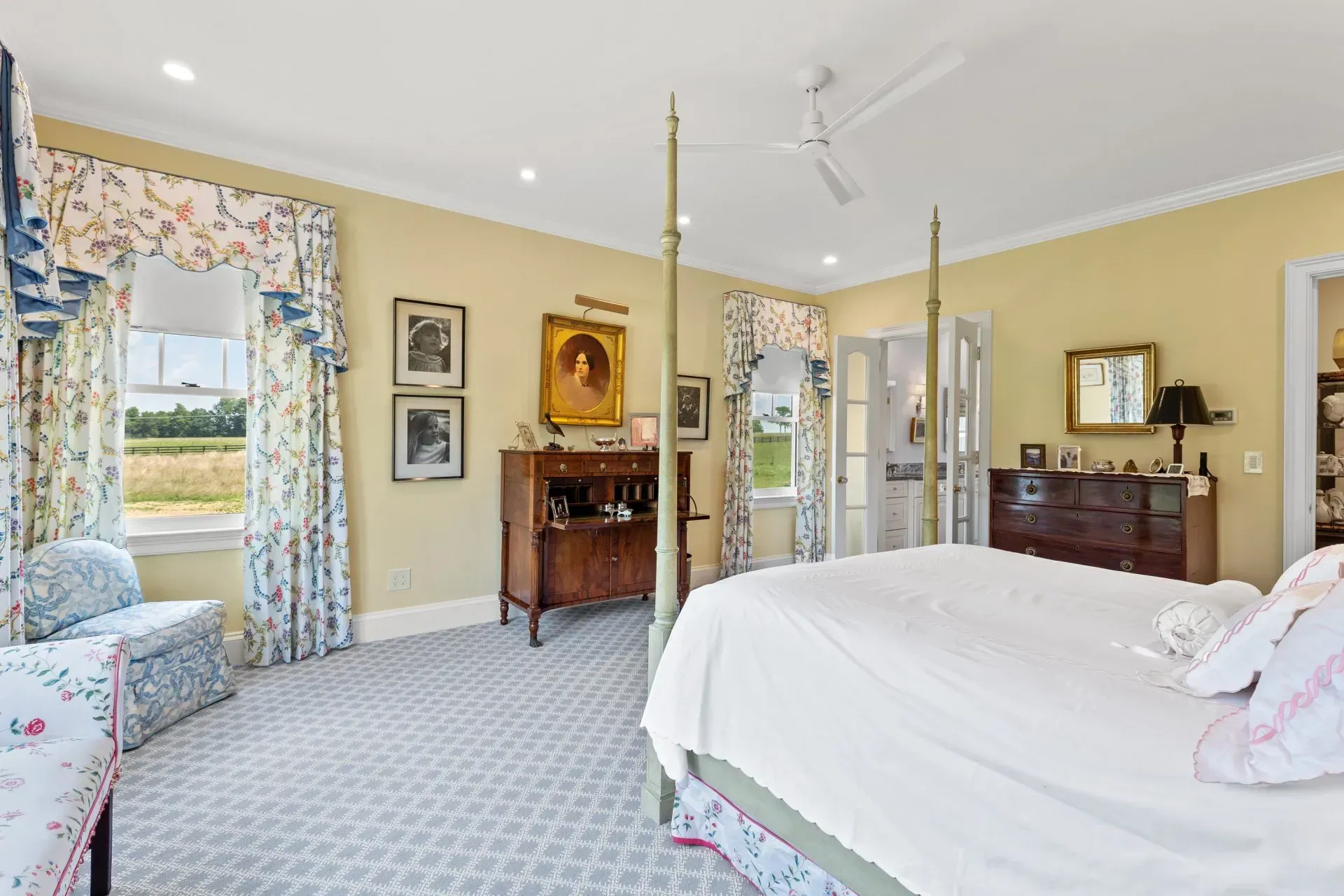 Spacious bedroom with a four-poster bed, floral curtains, yellow walls, and a sitting area.