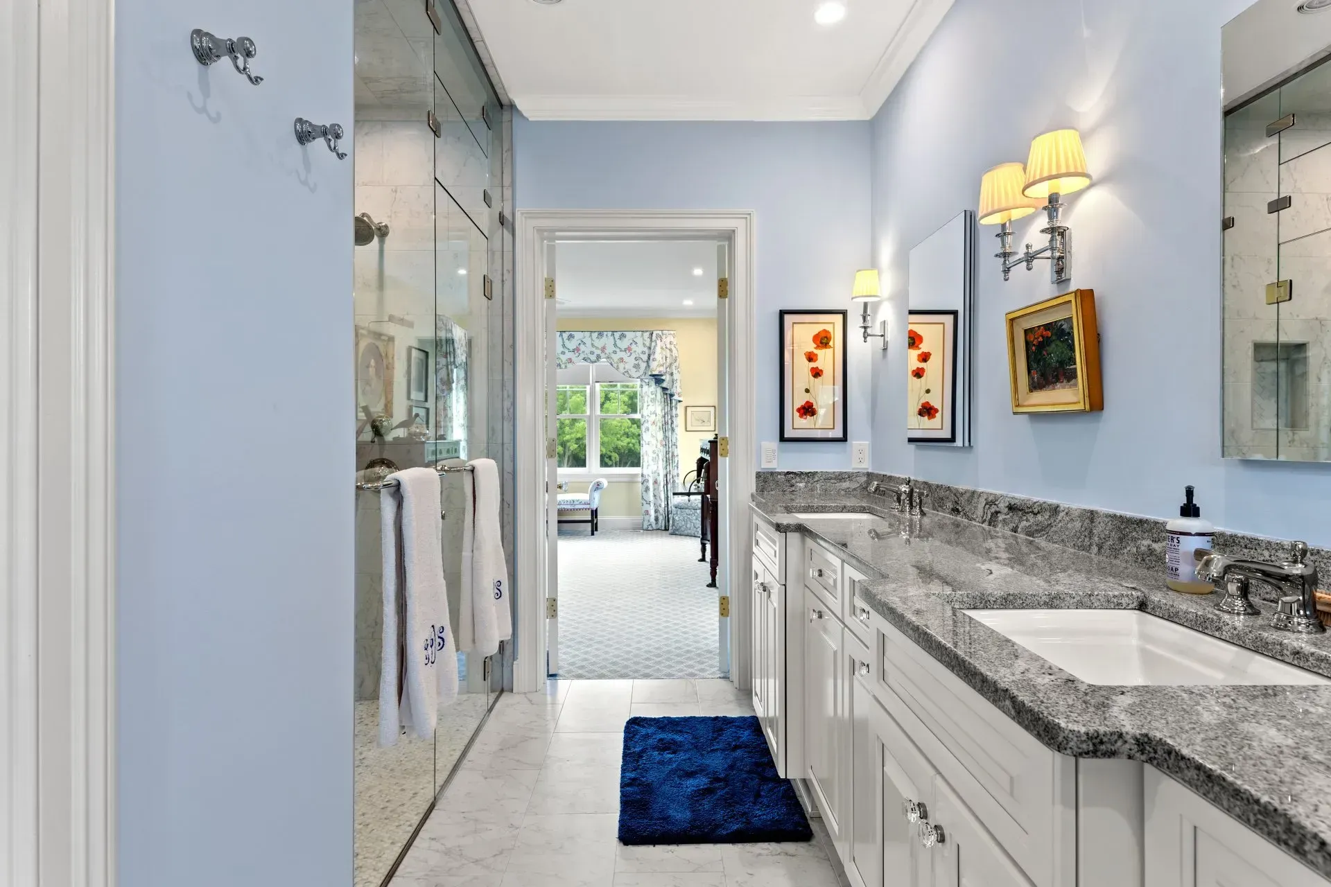 Bathroom with blue walls, white cabinets, grey countertop, and a long mirror.