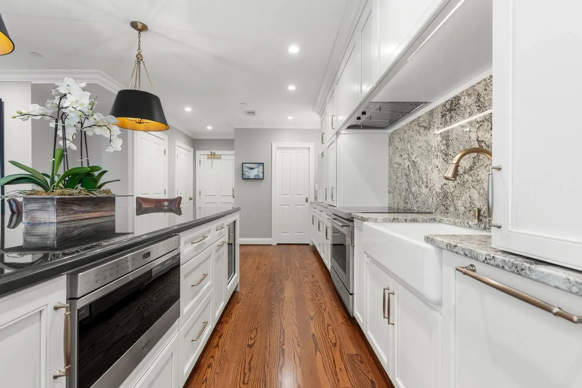 Elegant white kitchen with black island, granite counters, and stainless steel appliances.