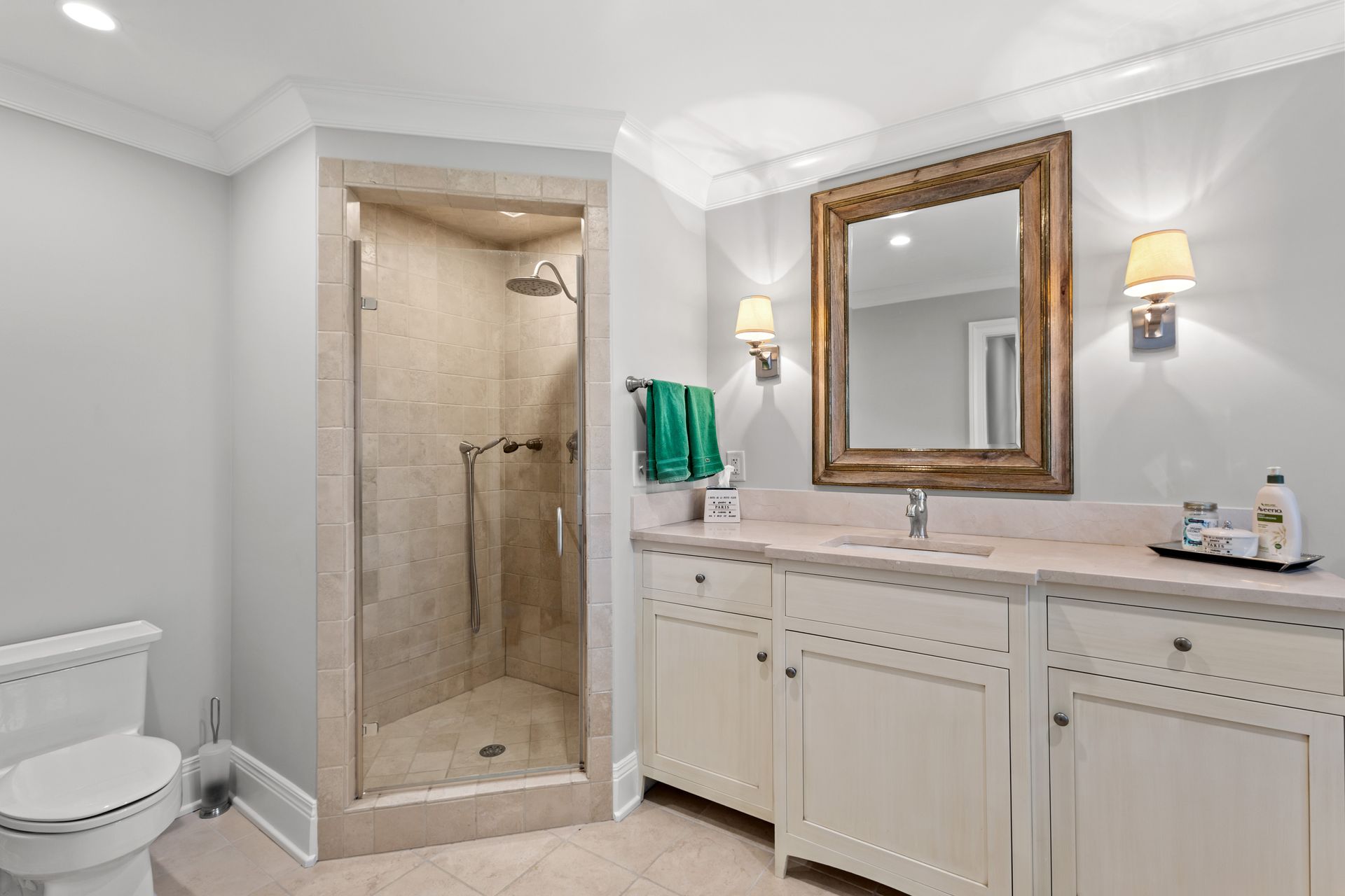 Bathroom with shower, toilet, sink, and mirror. Beige and white color scheme.