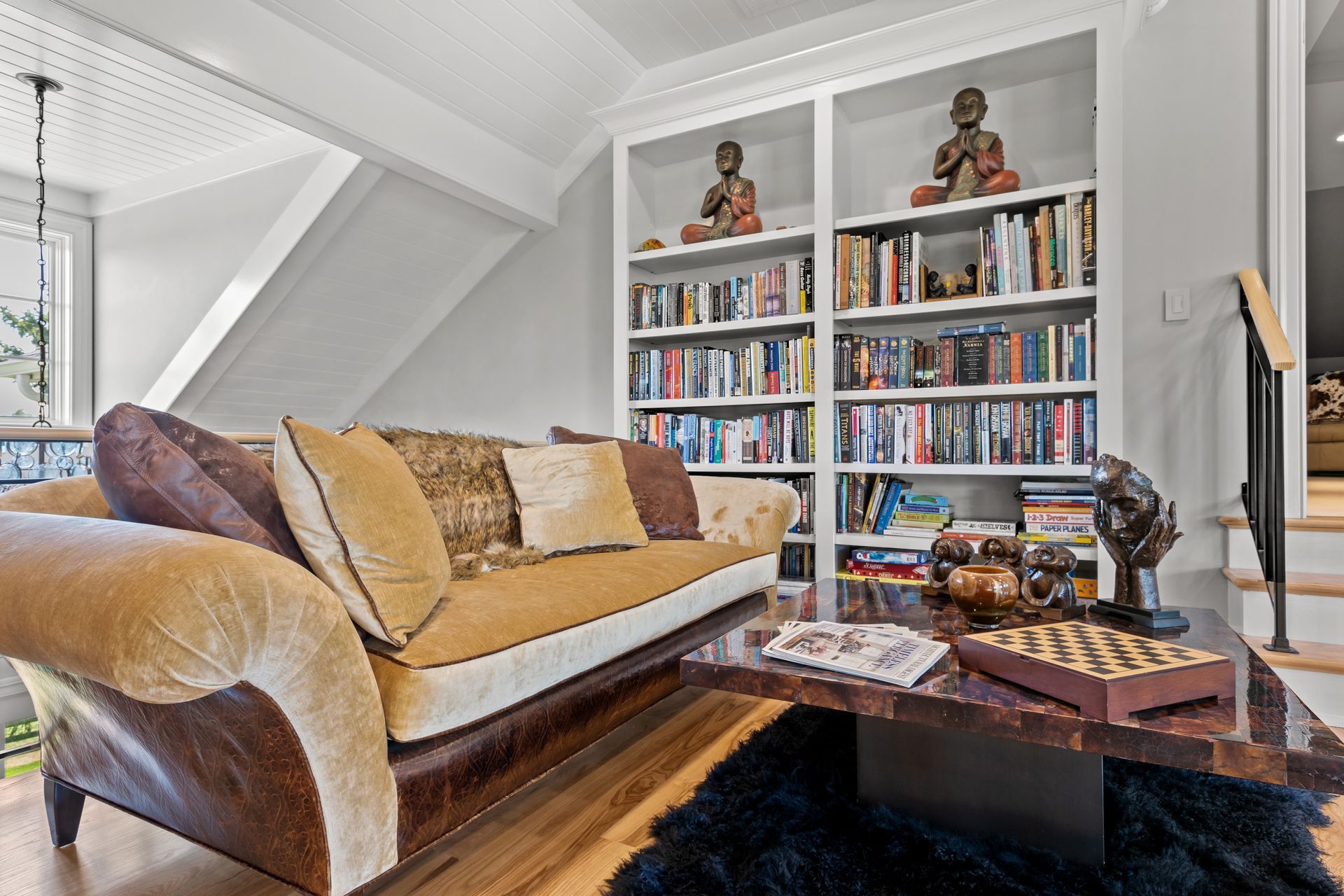Cozy living room with a yellow couch, bookshelves, and a dark wood coffee table.