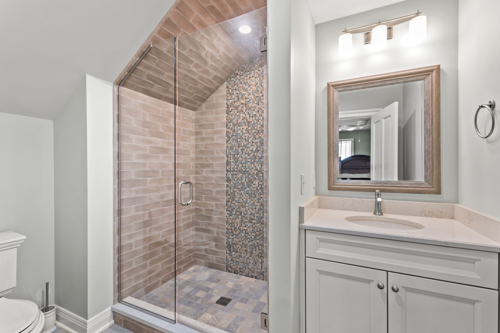 Bathroom with brick shower, glass door, white vanity, and light blue walls.