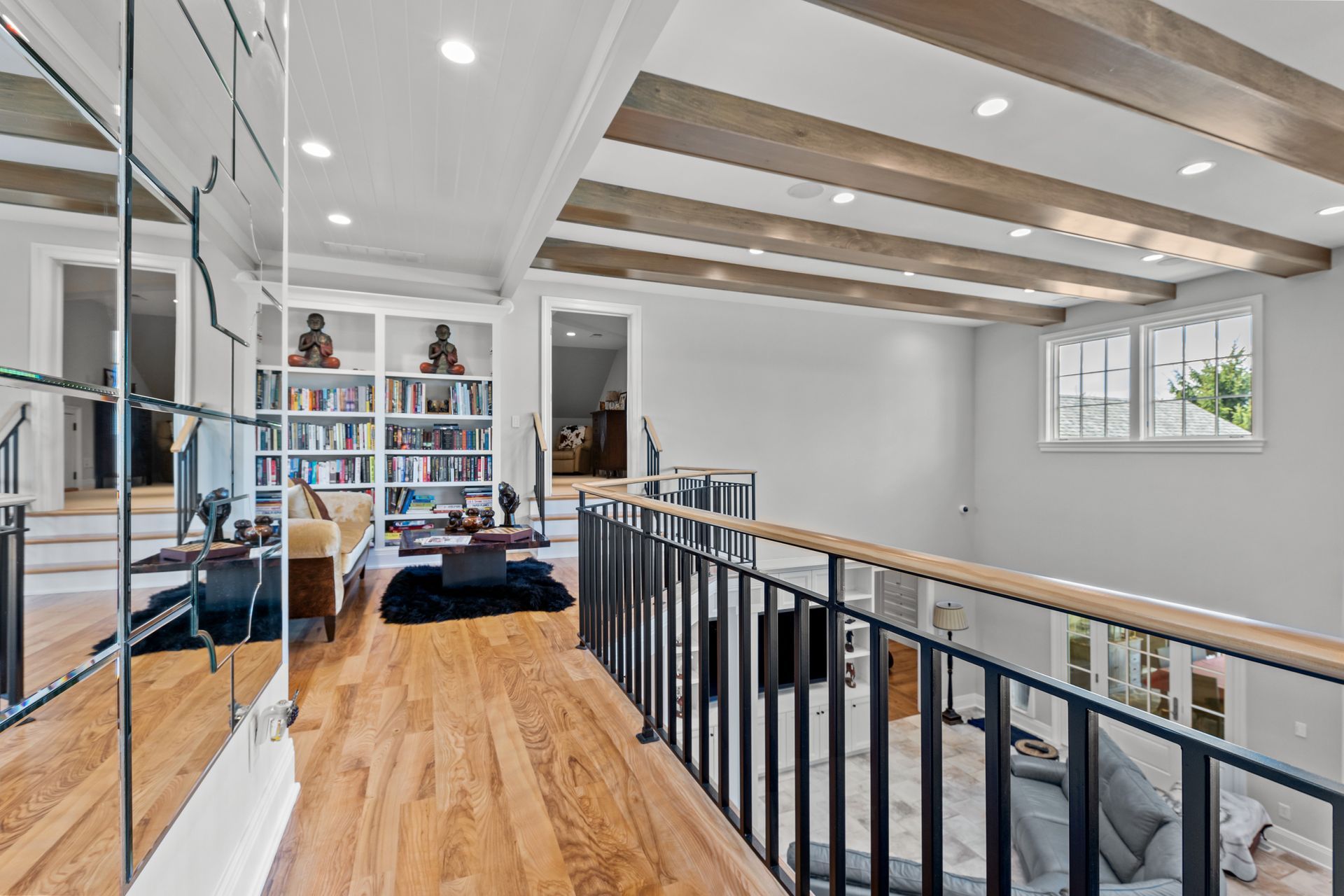 Interior view of a home's hallway with a staircase, railing, and bookcase.