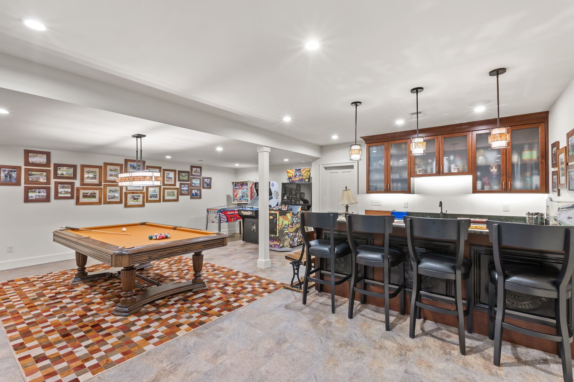 Basement with pool table, bar with stools, and a brown cowhide rug on a carpeted floor.