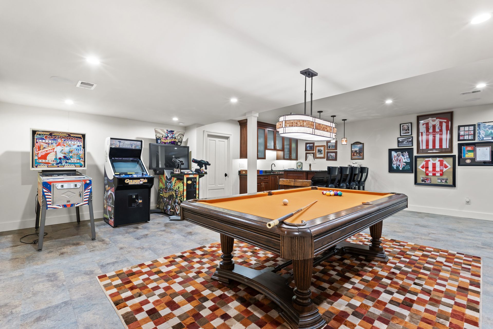 Game room with a pool table, arcade games, and a bar.