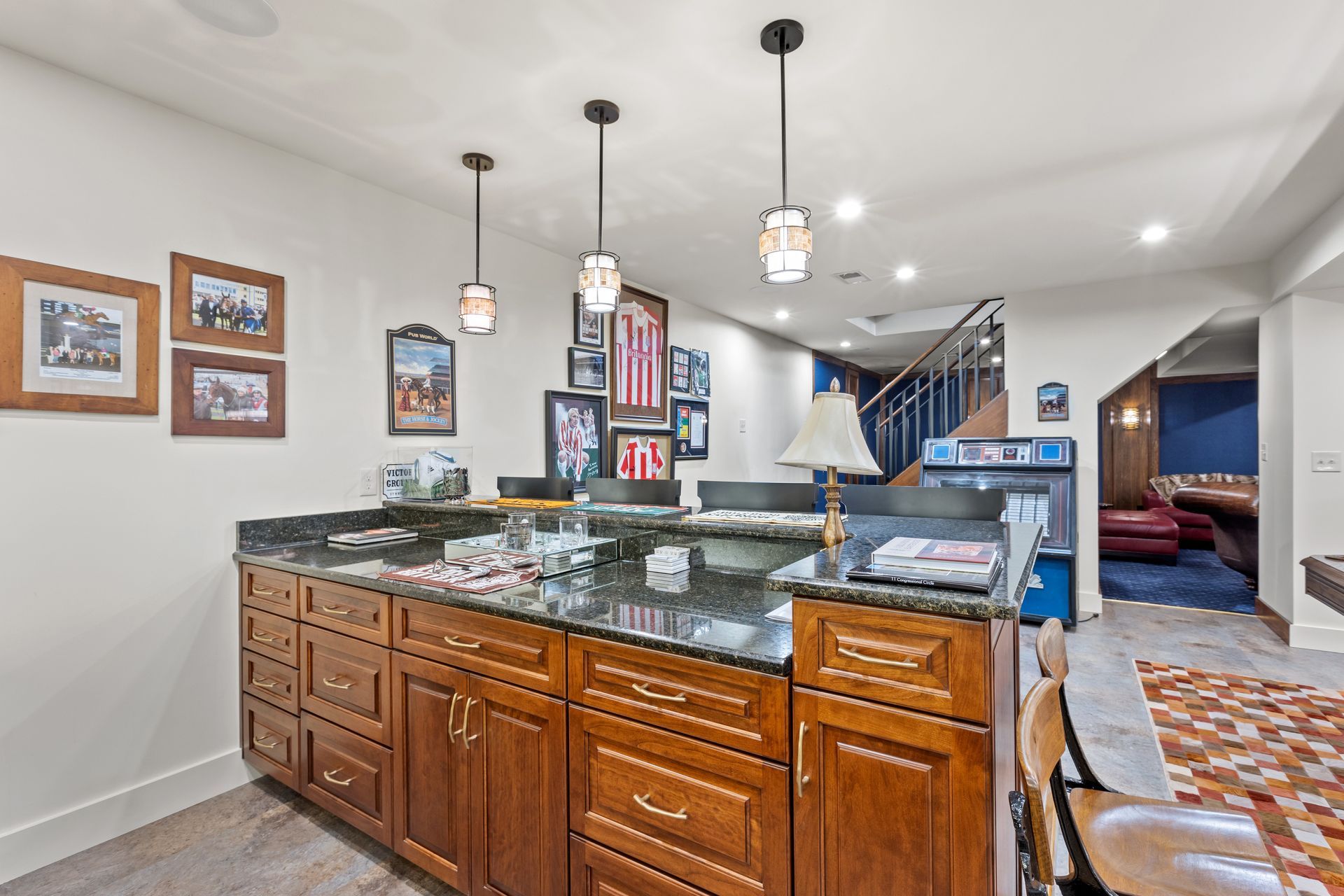 A home bar with a granite countertop and framed photos on the wall.