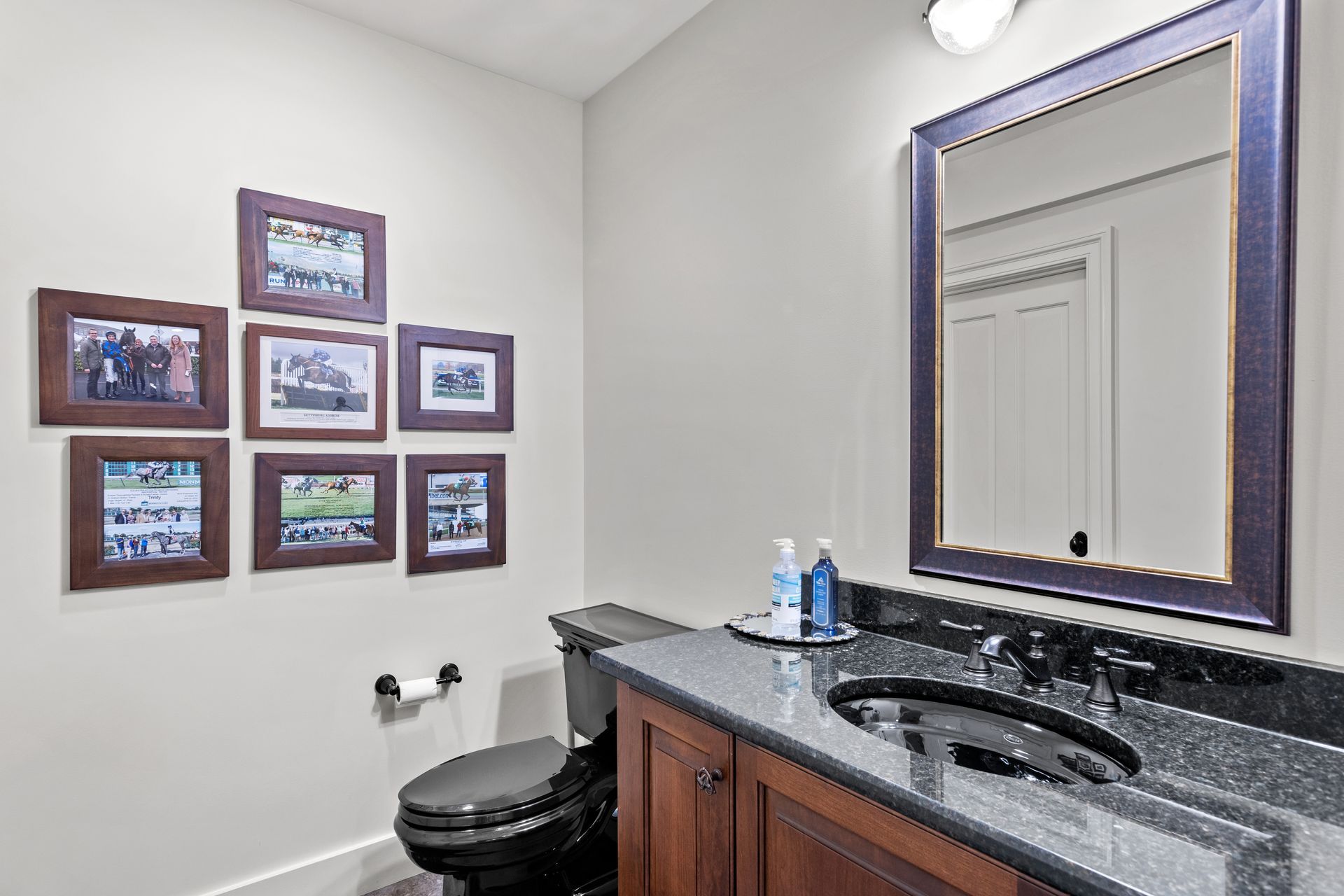 Bathroom with dark wood vanity, black granite countertop, and framed photos on the wall.