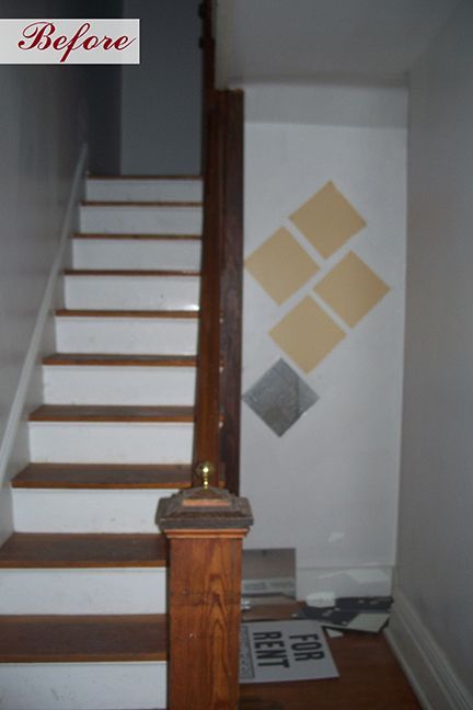 Staircase with wooden steps and railing. Creamy white walls and patterned wallpaper samples. 