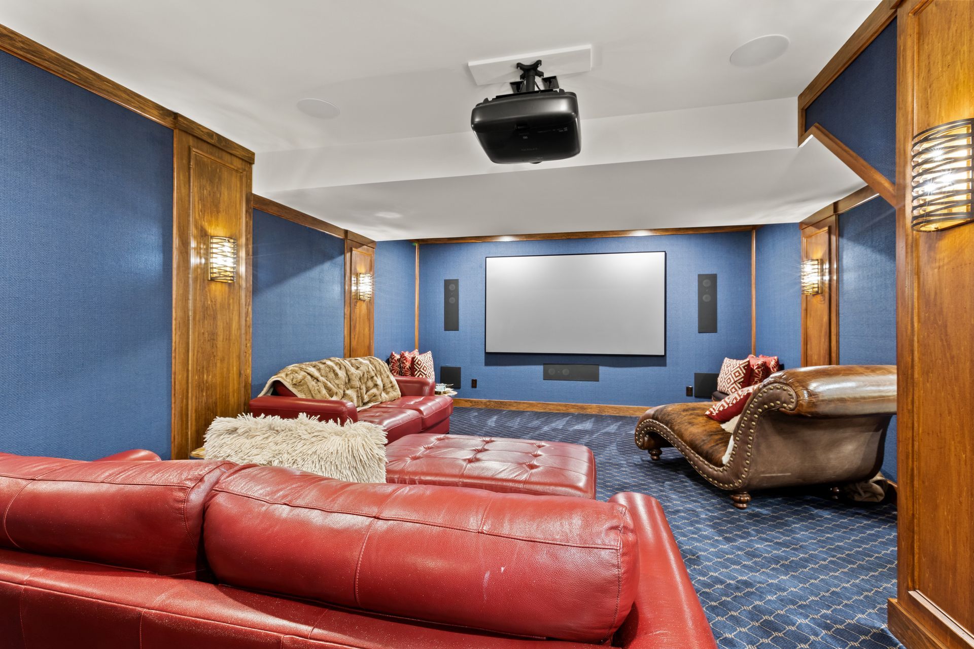 Home theater with a red couch, screen, projector, and blue walls.