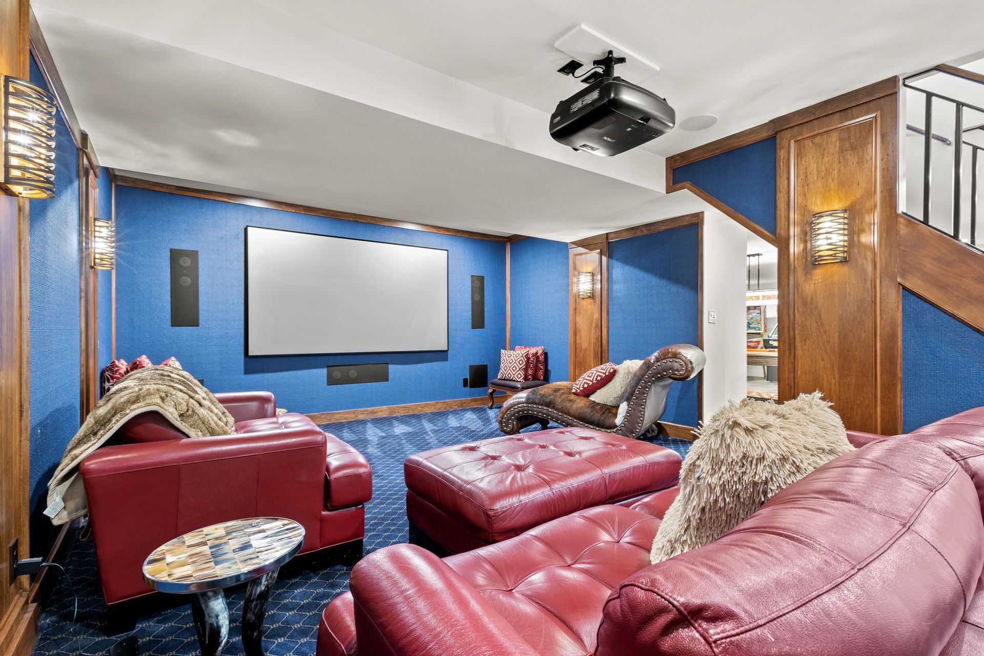 Home theater with red leather seating, blue walls, and a projector screen.