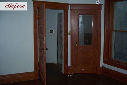 Wooden double doors, one open, leading to a room, with dark wood trim and a window.