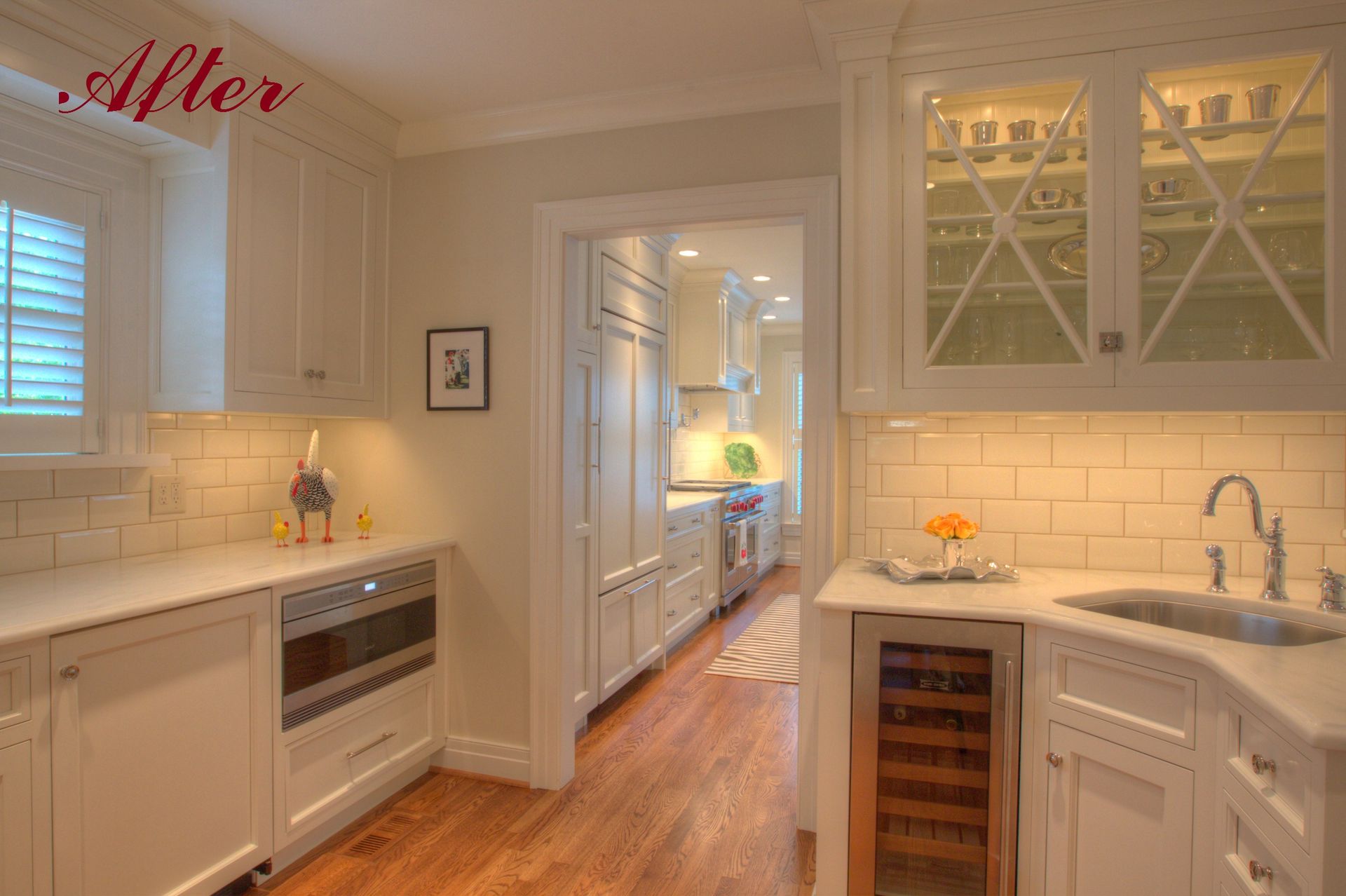 White kitchen with marble countertops, built-in appliances, and a doorway to a connected kitchen.
