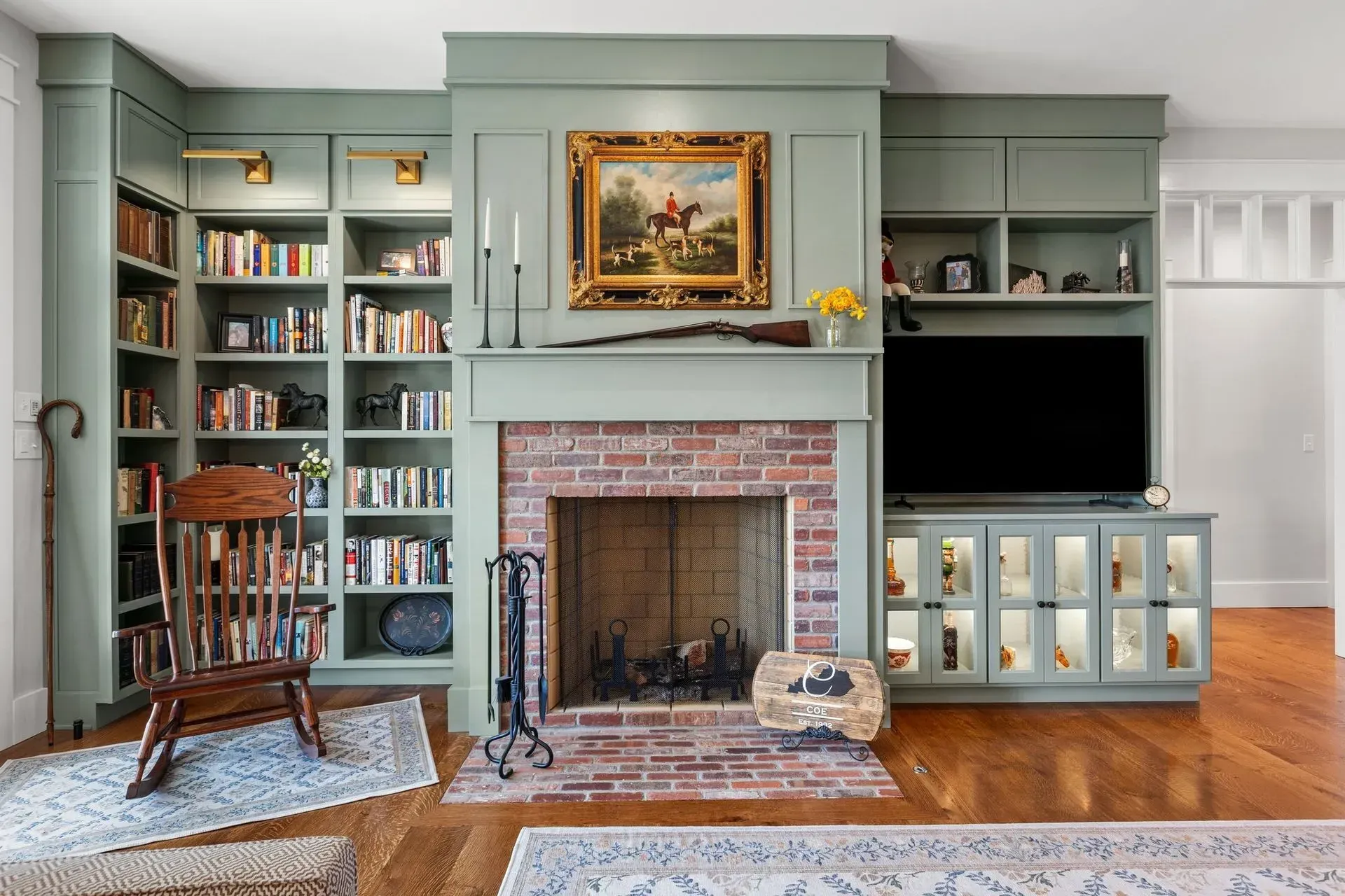Room with green bookshelves, fireplace, rocking chair, and television.