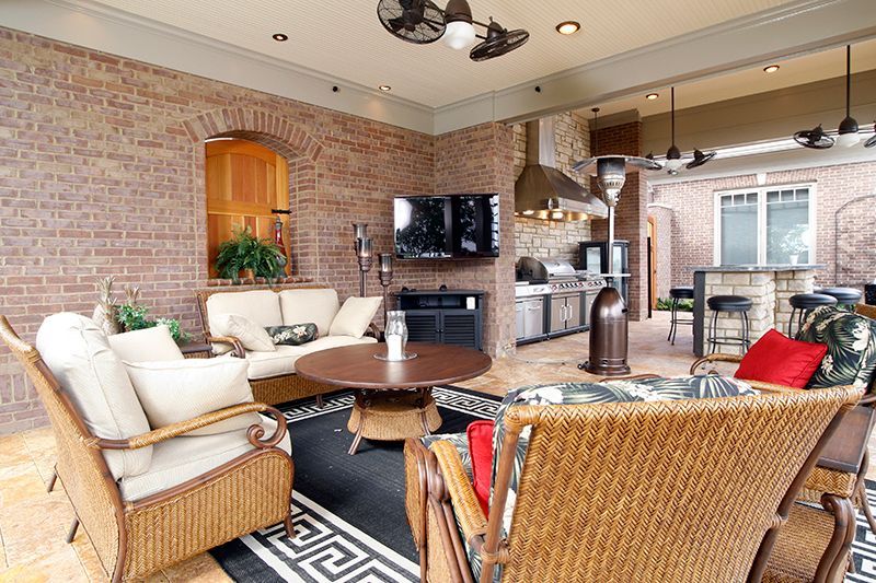 Outdoor patio with brick walls, seating area, fireplace, and kitchen.