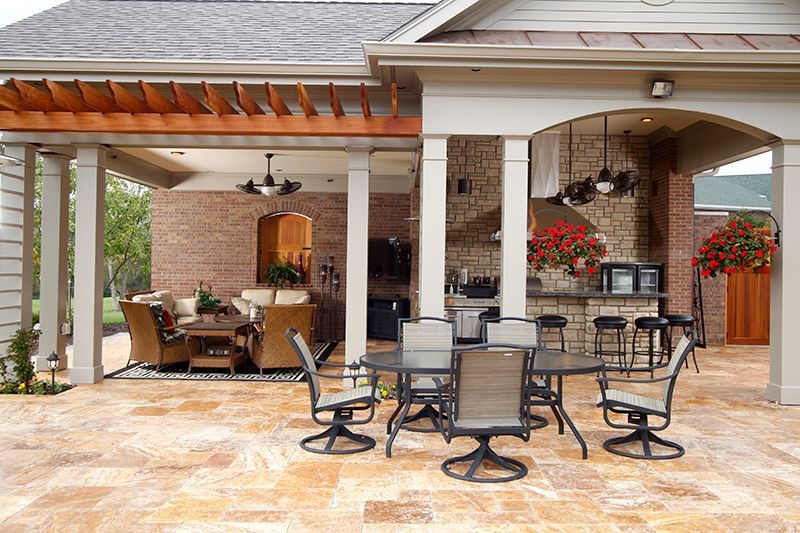 Outdoor patio with dining and lounge areas, brick and stone walls, and a pergola.
