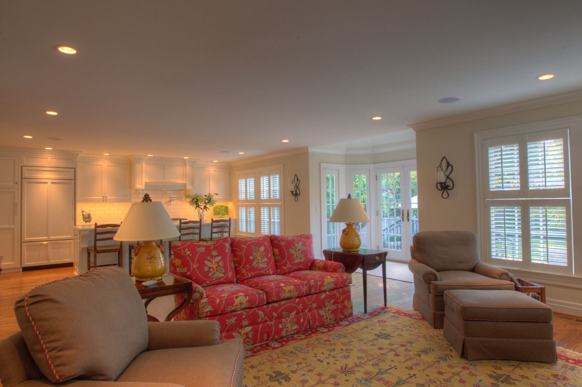 Living room with floral sofa, armchairs, and French doors to a bright patio.
