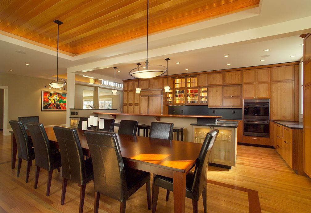 Spacious dining area with wood cabinetry, large table with black chairs, and recessed ceiling lighting.