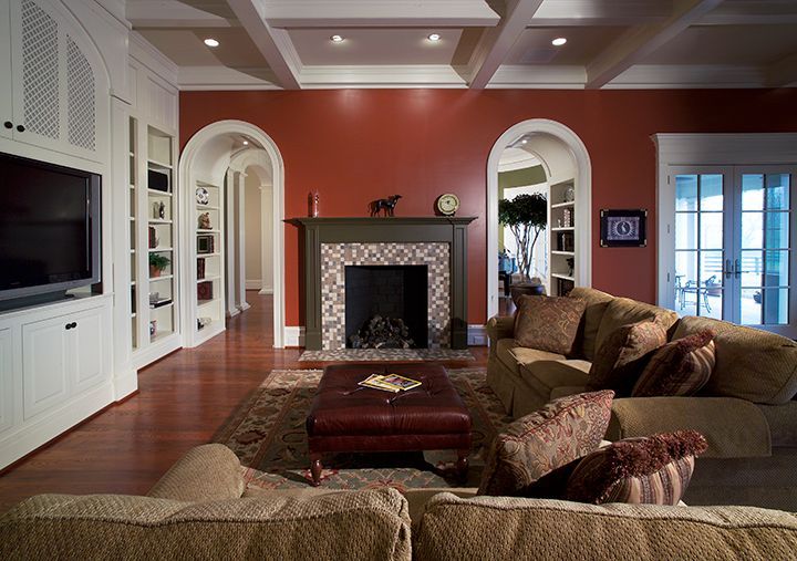 Living room with red walls, fireplace, built-in shelves, and beige couches.