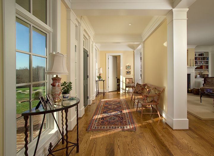 Bright hallway with hardwood floors, large windows, and a colorful rug.