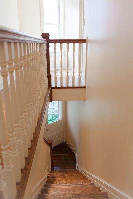 Wooden staircase with white railing and landing, viewed from above.