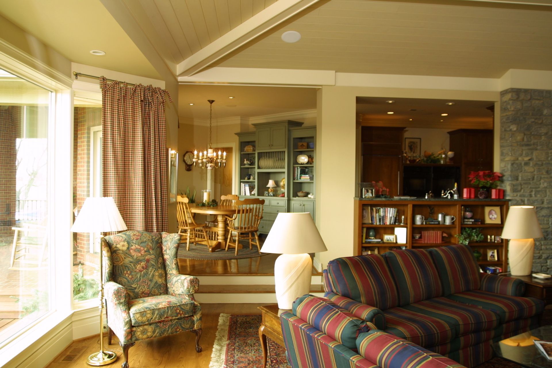Living room with patterned armchair, striped sofa, and doorway leading to dining area.