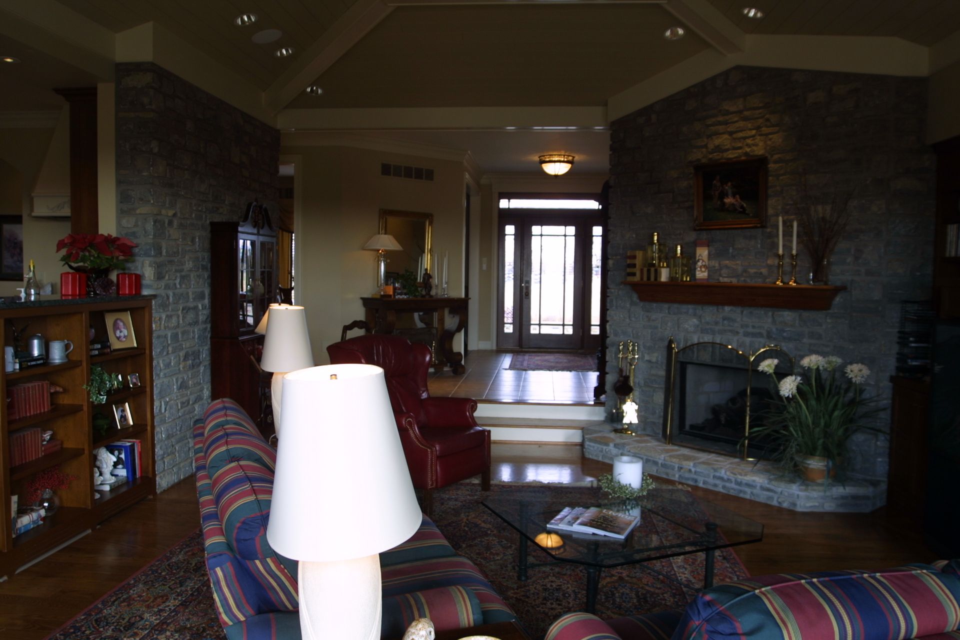 Living room with stone walls, fireplace, and furniture, lit by lamps.