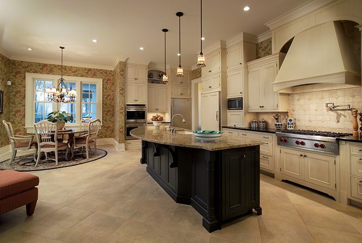 Elegant kitchen with large island, dining area, cream cabinets, stainless steel appliances.