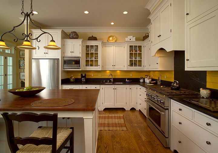 Cozy white kitchen with island, stainless steel appliances, and yellow backsplash.