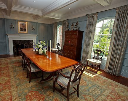 Formal dining room with long wooden table, chairs, fireplace, and blue walls.