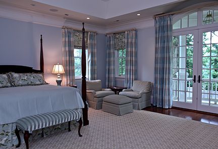 Bedroom with a four-poster bed, two armchairs, and French doors leading to a balcony. Blue and white color scheme.