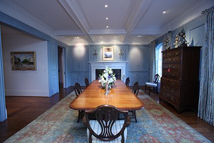 Elegant dining room with long wooden table, chairs, fireplace, and blue walls.