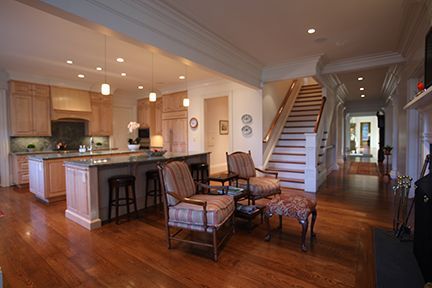 Open-concept kitchen and living area with hardwood floors, stairs, and seating.