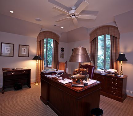 Home office with desk, lamps, windows, and framed artwork.