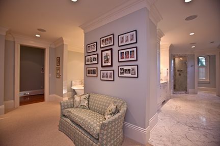 Spacious bathroom with light blue walls, white trim, seating, and framed photos.