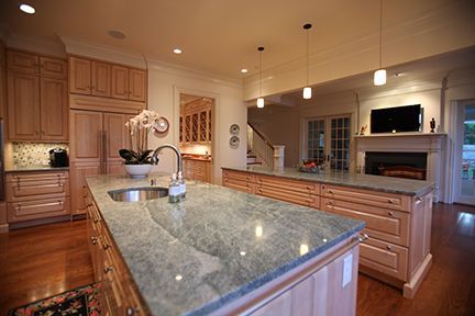 Spacious kitchen with light wood cabinets, large island with granite countertop, and fireplace.