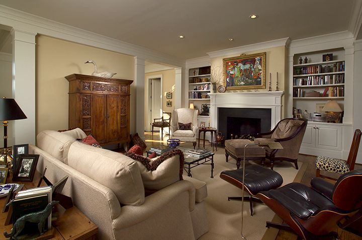 Living room with beige sofa, wood cabinet, fireplace, and modern black leather recliner.