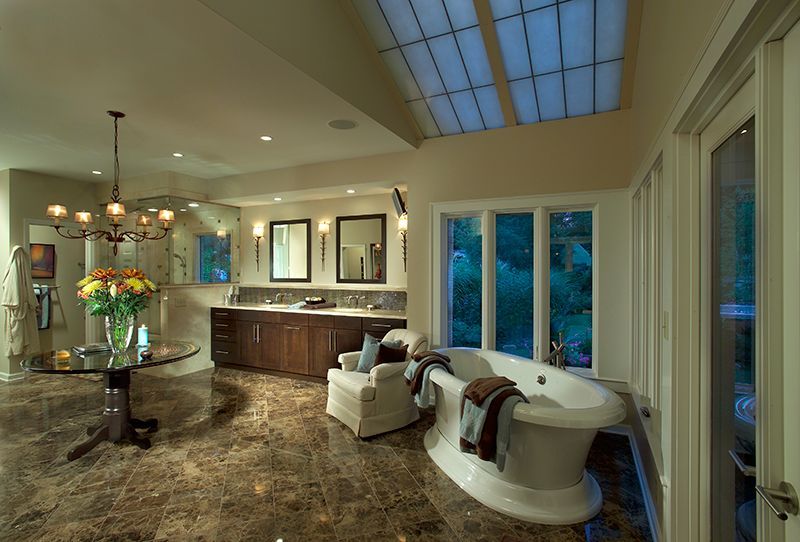 Luxurious bathroom with a large tub, dark wood vanity, and marble floors.