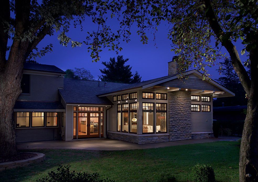 A craftsman-style house at night, illuminated by warm interior lights.
