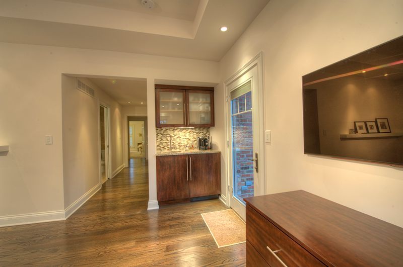 A hallway with a dark wood cabinet, door, and a long passage.