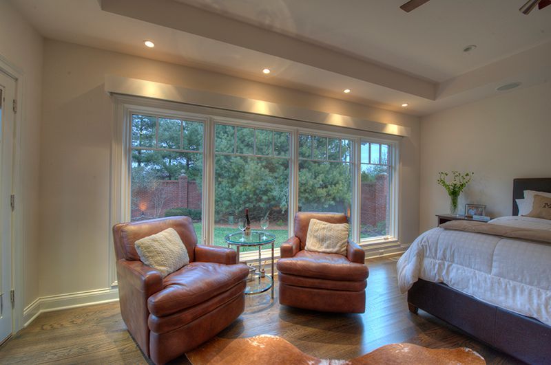 Bedroom with leather armchairs facing large windows overlooking a lush garden.