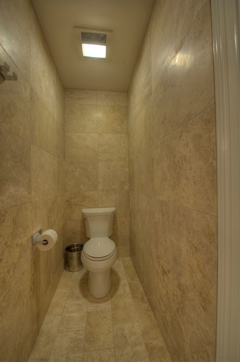 Small, narrow bathroom with light beige tile walls and a toilet.
