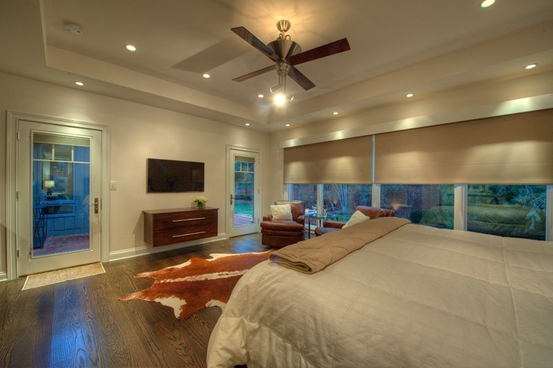 A bedroom with a king-size bed, a dresser with a TV, and an outdoor view.