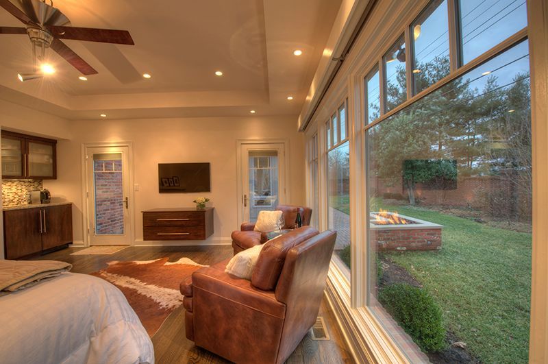 Living room with leather chairs, large windows overlooking a backyard with a fire pit.