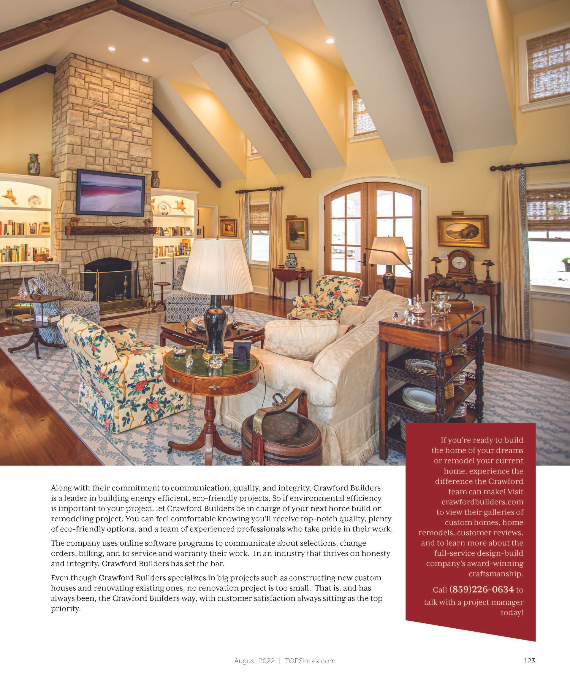 Living room with high ceilings, stone fireplace, floral sofa, wood beams, and glass doors.